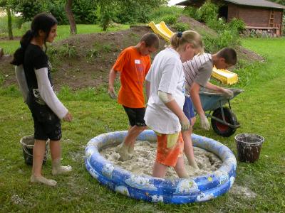 Zuerst muss der Lehm mit Wasser verdünnt und kräftig gestampft werden.
<br />
Eine Arbeit, die müde macht! Aber das Gatschen macht den meisten Kindern große Freude!