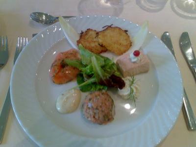 Auf einem Teller sind verschiedene Lachsvariationen und zwei Rösti kunstvoll angerichtet