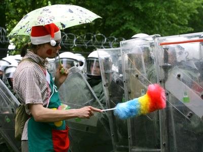 ein_verkleideter_demonstrant_provoziert_mit_einem_staubwedel_die_polizei