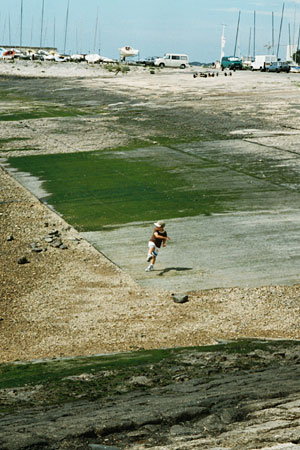 ein kind (baseballer??) wirft steine ins meer, hafeneinfahrt la rochelle