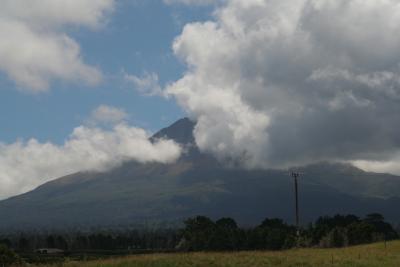 Mt. Taranaki von Sueden aus gesehen. Der komplette obere Teil ist von Wolken bedeckt.