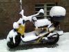Ein Motorroller ist unter 10 cm Schnee zum Teil verborgen