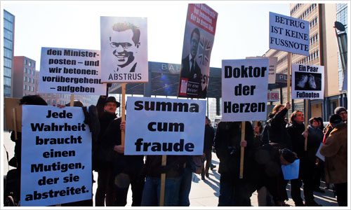 Menschen mit Plakaten gegen Guttenberg