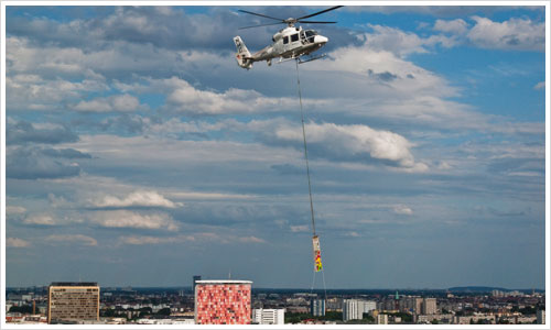 Hubschrauber mit angehängten Mauerstück über Berlin